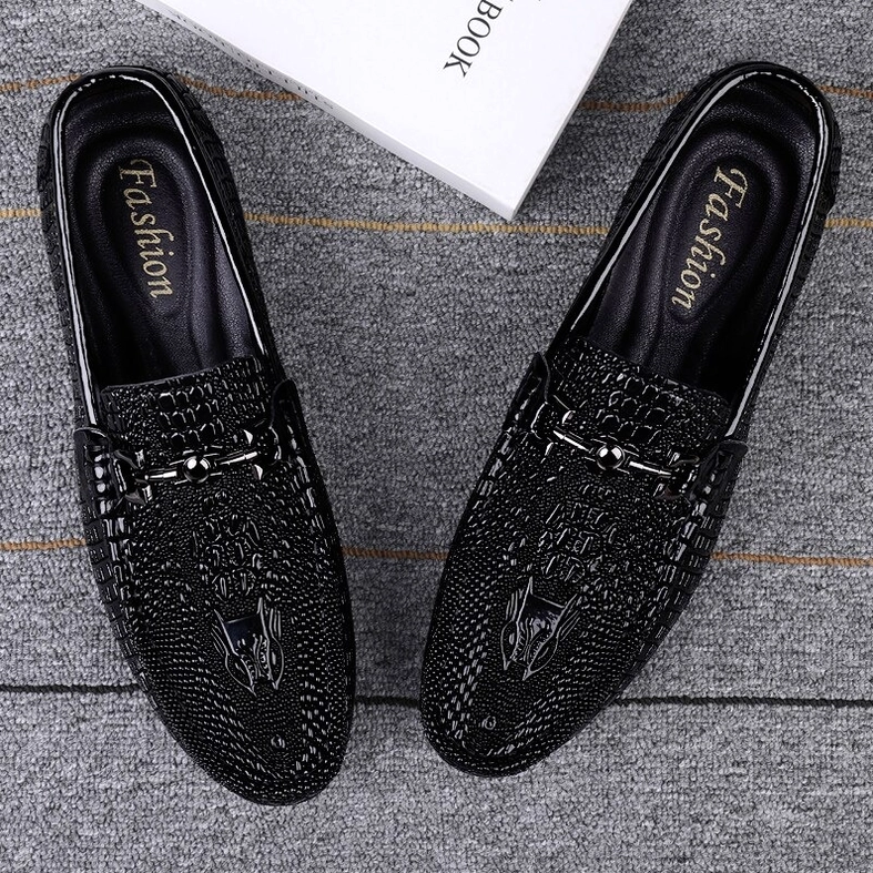 Top-down flat view of paired black gothic leather loafers with metal horse-bit decoration on gray carpet background