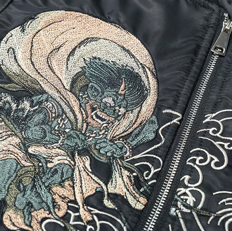 Front embroidery close-up - colorful oni demon and wave stitching on black bomber jacket with precision thread work