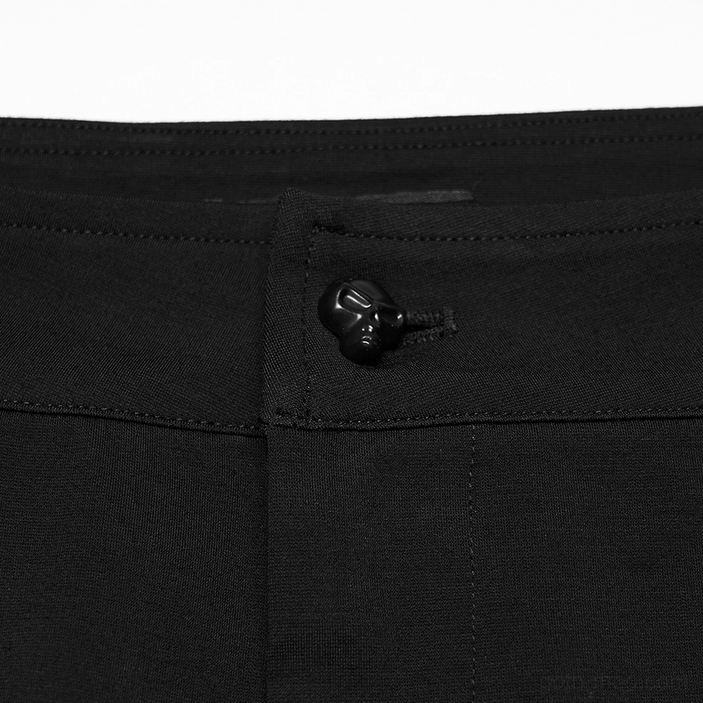 Close-up detail shot of gothic pants waistband featuring skull-embossed button and precision stitching