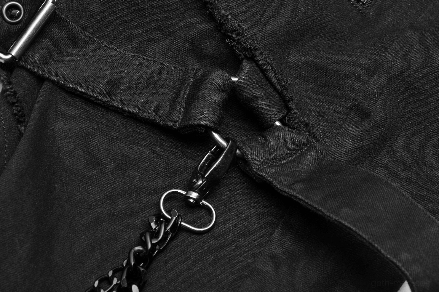 Close-up detail of black fabric strap with metal clip fastener and attached chain on Gothic pants