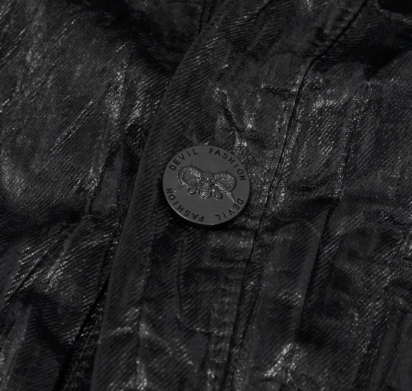 Close-up of gothic black punk rock shirt embossed branded button on crinkled fabric
