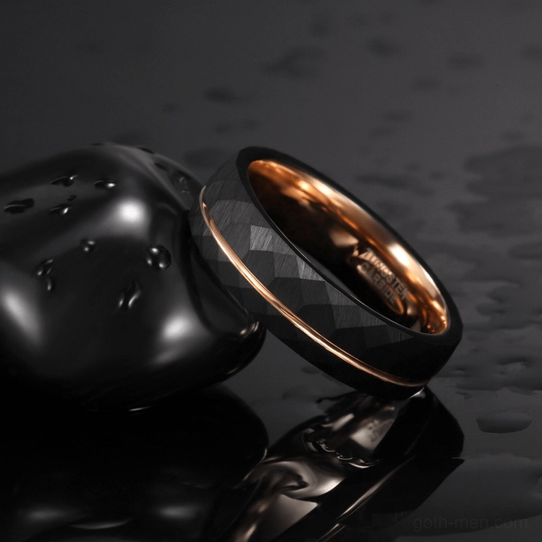 Matte black gothic faceted tungsten ring with rose gold interior on wet dark surface