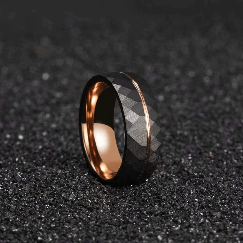 Black and rose gold gothic rhombus faceted ring on dark gravel background