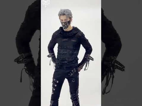 Male model wearing black gothic ripped hoodie with face mask, front pose with hands on hips against dim studio background