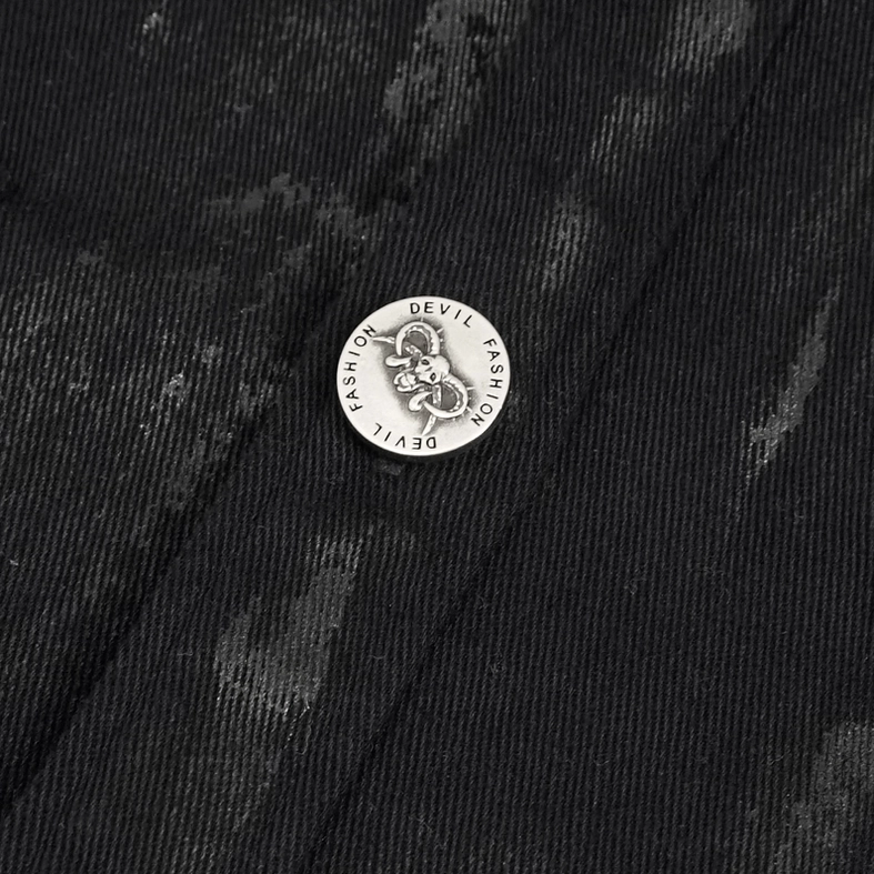 Close-up of gothic shirt button and woven fabric showing branded metal button and faded black texture