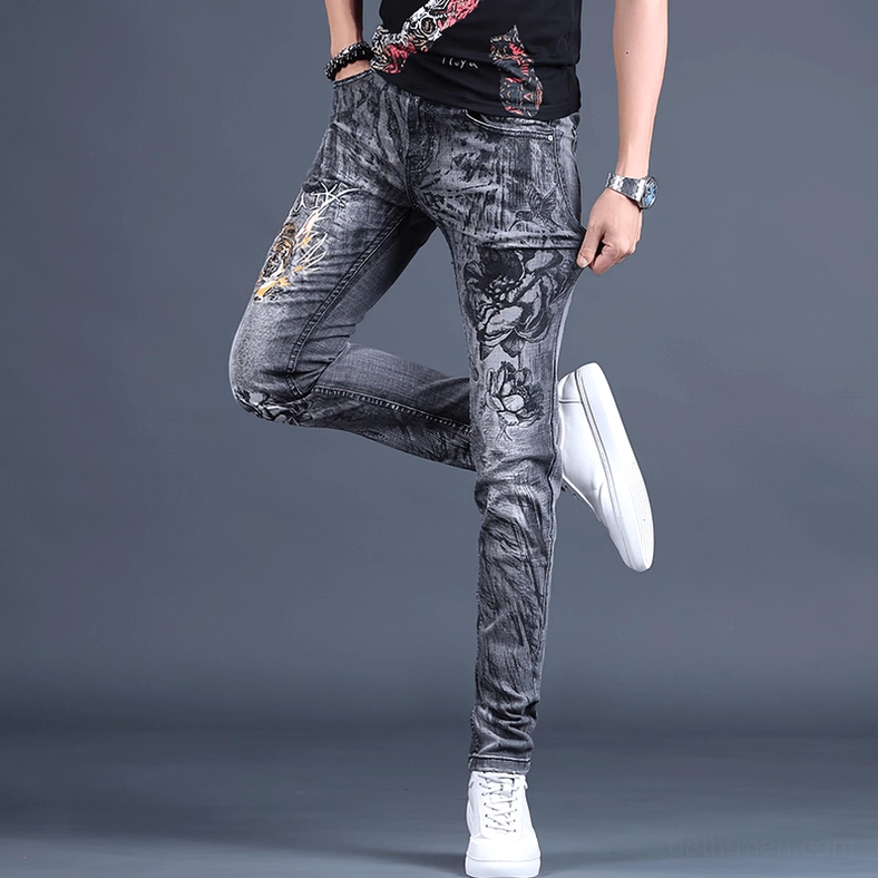 Low three-quarter side view of men's gothic embroidered denim pants with floral embroidery detail on leg
