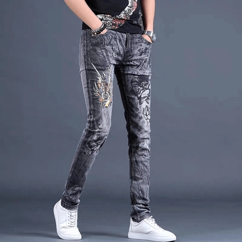 Three-quarter side view of men's gothic embroidered denim pants showing detailed floral and dragon embroidery