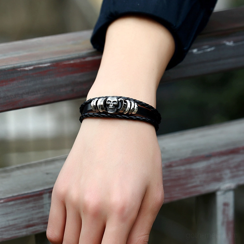 Black gothic skull bracelet worn on wrist outdoors showing side profile and silver metal details on natural wooden background
