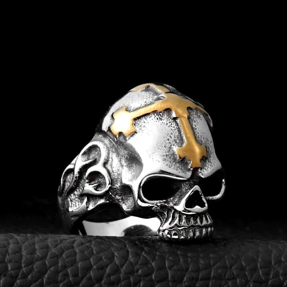Two-tone gold and silver stainless steel skull cross ring, polished front view showcasing architectural skull structure and carved band details