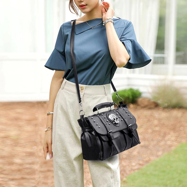 Female model wearing black gothic skull handbag crossbody style in outdoor garden setting alternative fashion