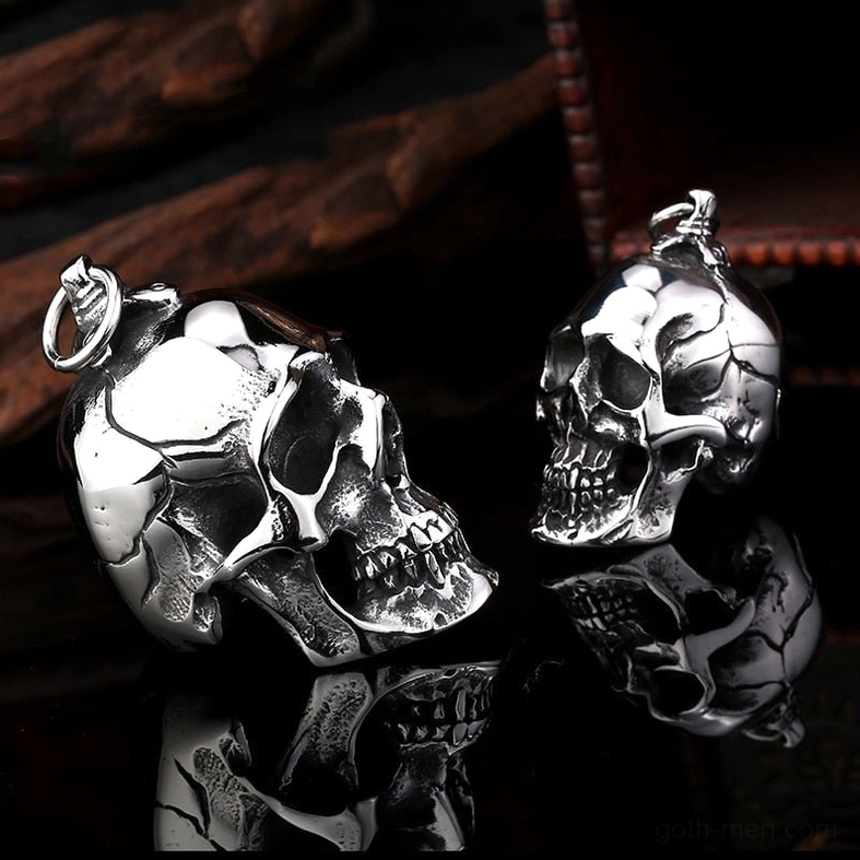 Reverse side view of dual skull pendants showing intricate carving detail on reflective black background