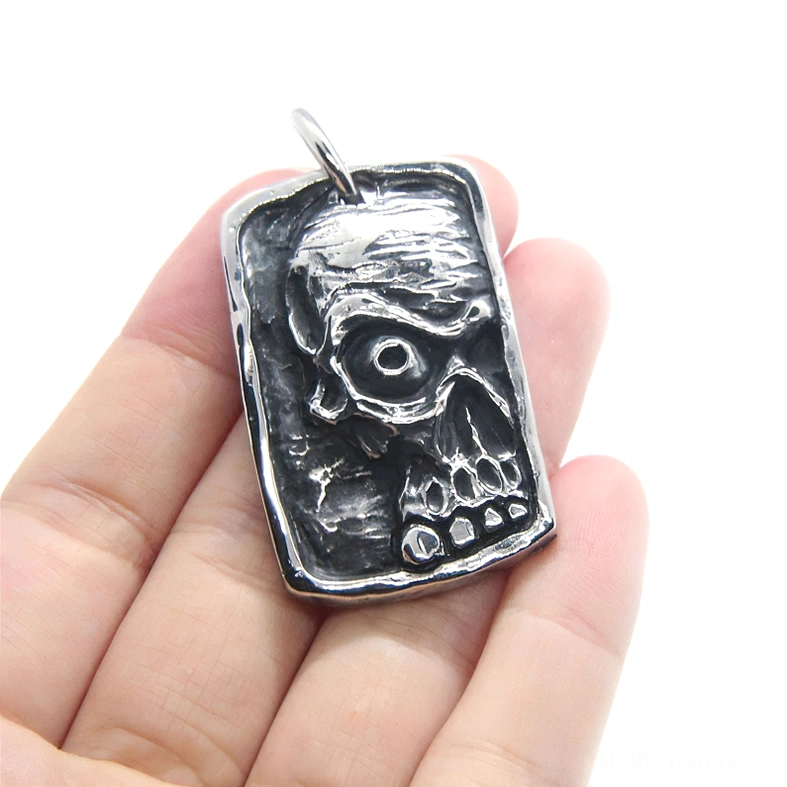 Overhead view of ghost skull dog tag pendant resting on human palm showing detailed embossed skull design and scale