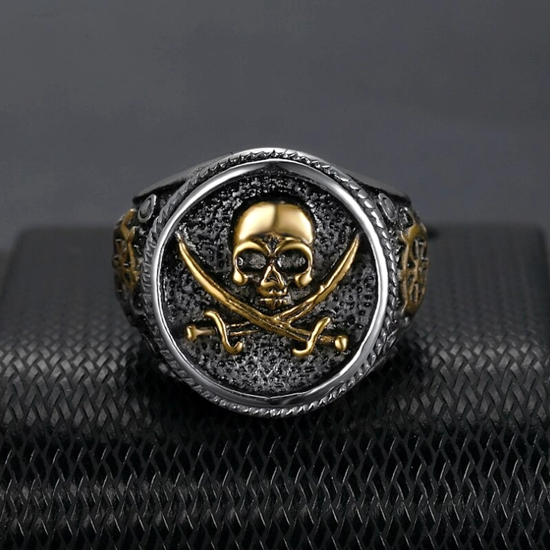 Two-tone gothic skull pirate signet ring with gold skull design and braided frame on black leather pad, top view