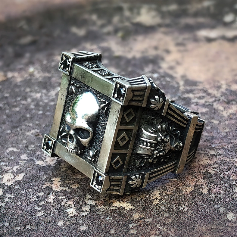 Gothic skull ring front-side low angle view with side engraved patterns and corner gem accents on stainless steel