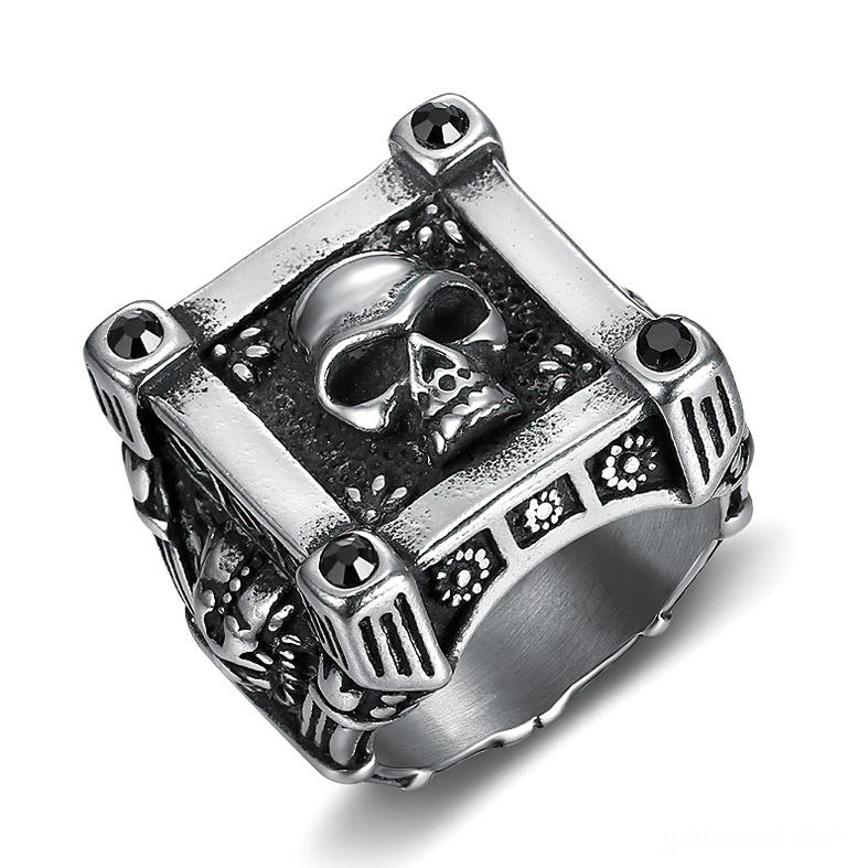Stainless steel gothic skull ring with geometric frame and black diamond accents, top-left oblique view showing engraved floral side patterns