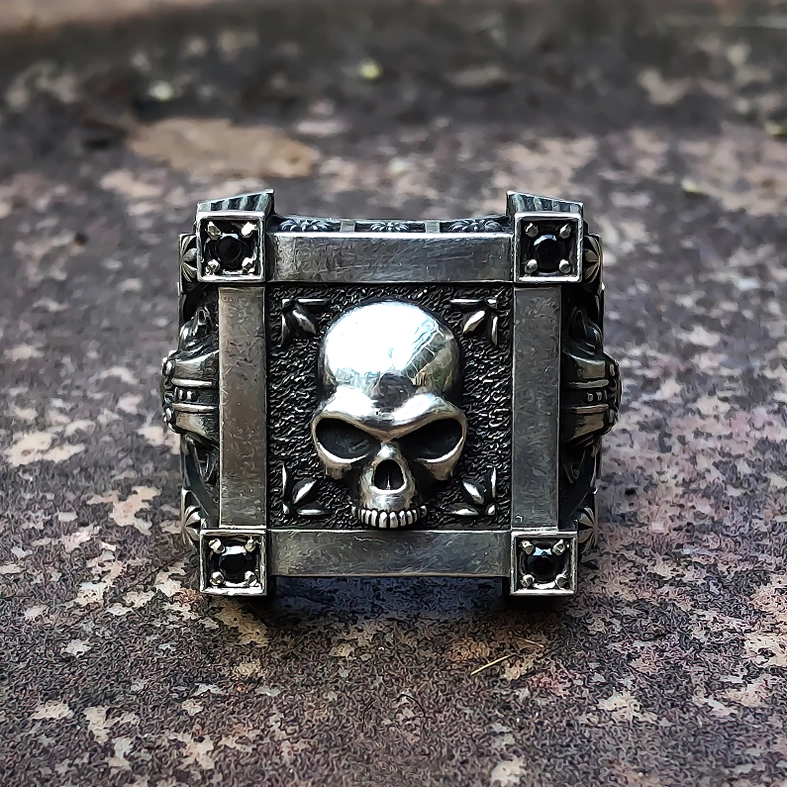 Dark gothic skull ring direct front view with black gem accents, antique silver finish on weathered surface