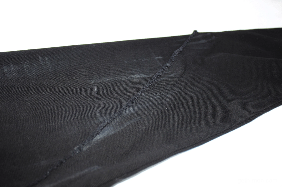 Angled view of black gothic slim trousers highlighting distressed paint splatter and artistic texture
