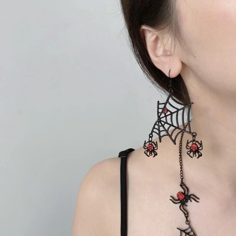 Matching gothic spider earrings and necklace set with red rhinestone accents worn on model, side view on gray background