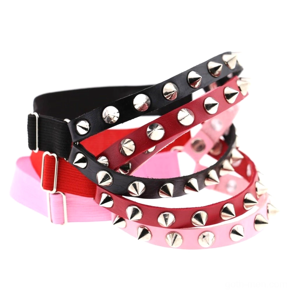 Multiple adjustable spiked knee garter belts displayed in studio flat lay, showcasing mixed metal studs and color variety for gothic aesthetic