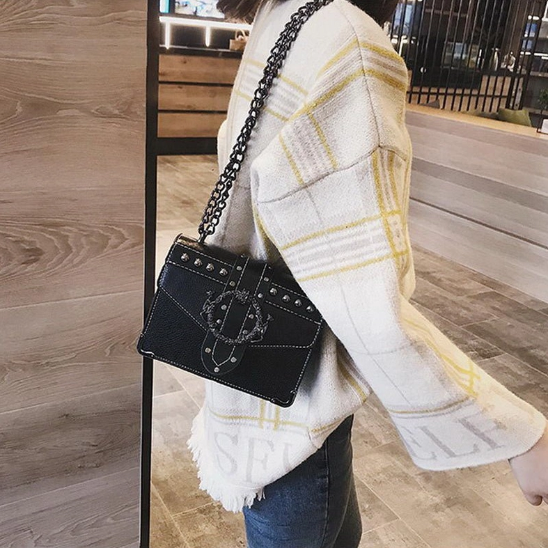 Woman wearing black gothic square shoulder bag as crossbody, side view in urban setting
