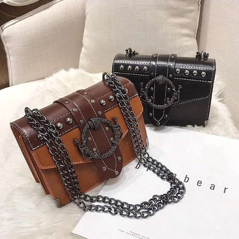 Tan and black gothic square shoulder bags styled on fur cushion showing chain strap detail