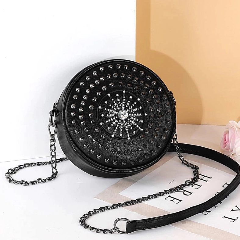 Black circular rivet gothic shoulder bag displayed on desktop with chain strap and leather shoulder pad detail