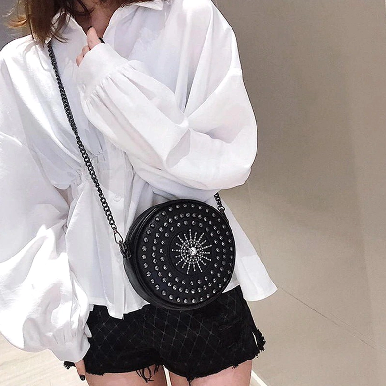 Female model carrying black rivet round bag on shoulder with white blouse outfit, daily casual styling
