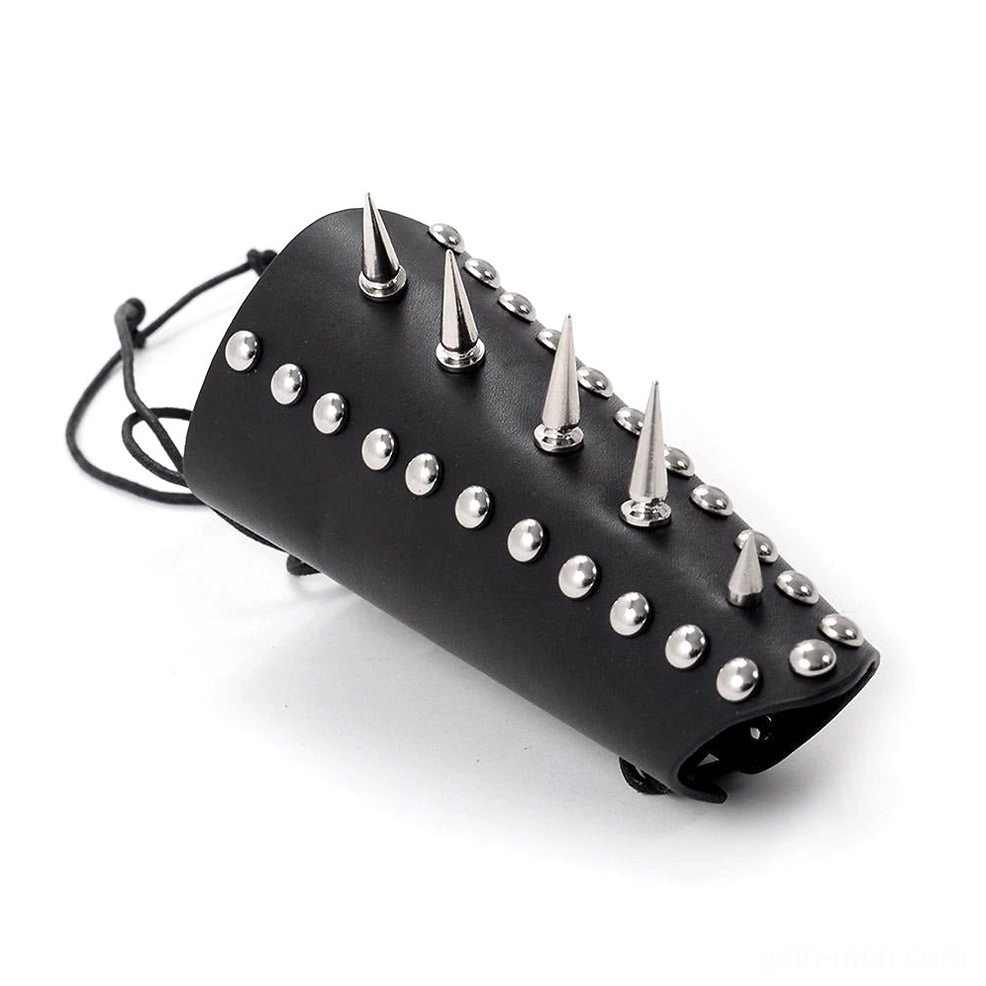 Black studded leather wrist guard with cone spikes and round metal studs, three-quarter angle view showing aggressive spike detailing and lace-up closure system