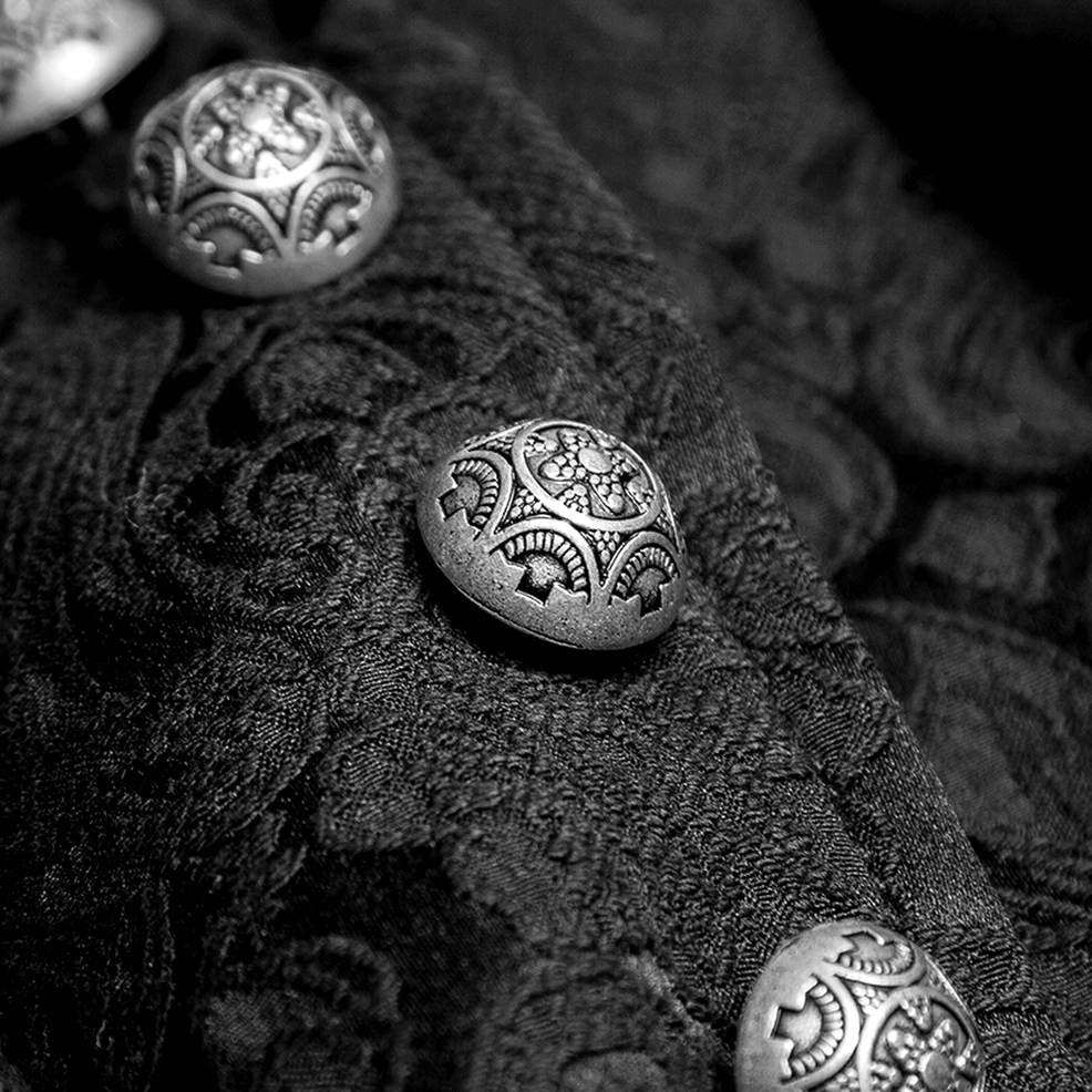 Close-up macro detail of embossed black lace jacquard fabric and vintage engraved metal buttons