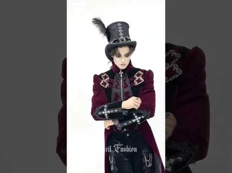 Gothic tailcoat detail shot showing feather top hat, cross-shaped shoulder hardware, and cuff embellishments on model