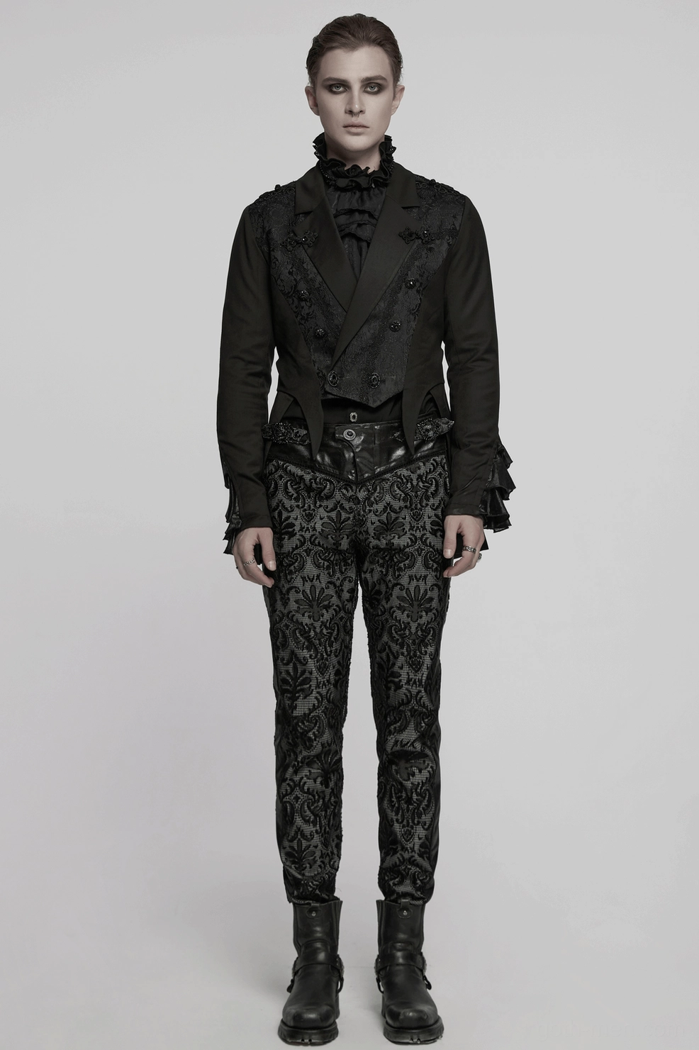 Black gothic tailcoat on male model displaying full silhouette with gemstone buttons, embroidered panels, and dramatic ruffled cuffs