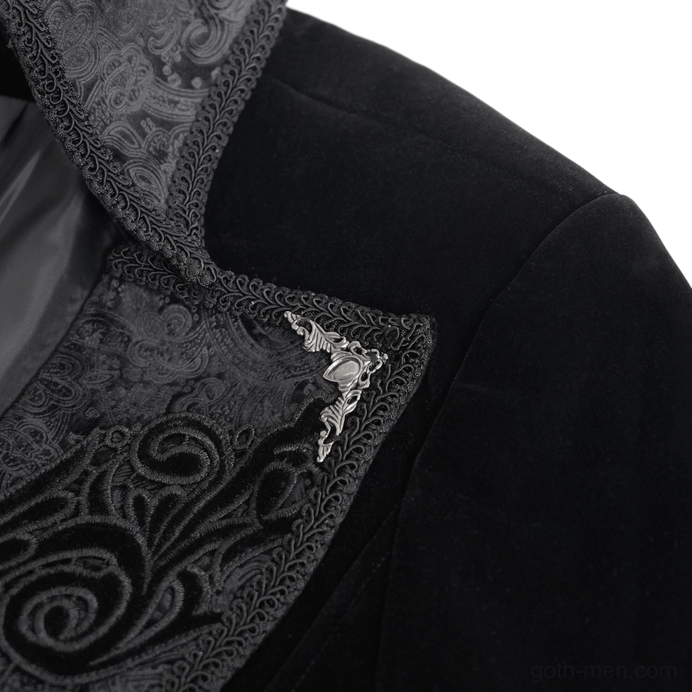 Close-up detail of embroidered scroll lapel on black velvet tailcoat, showing ornate metallic brooch and intricate embroidery craftsmanship
