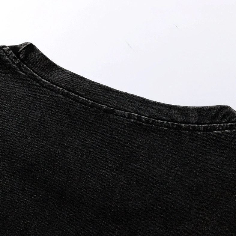 Fabric texture close-up showing distressed black cotton with stitched trim details