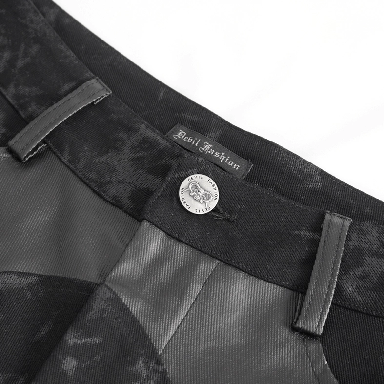 Close-up detail of gothic trousers waistband featuring branded metal button and leather fabric patches