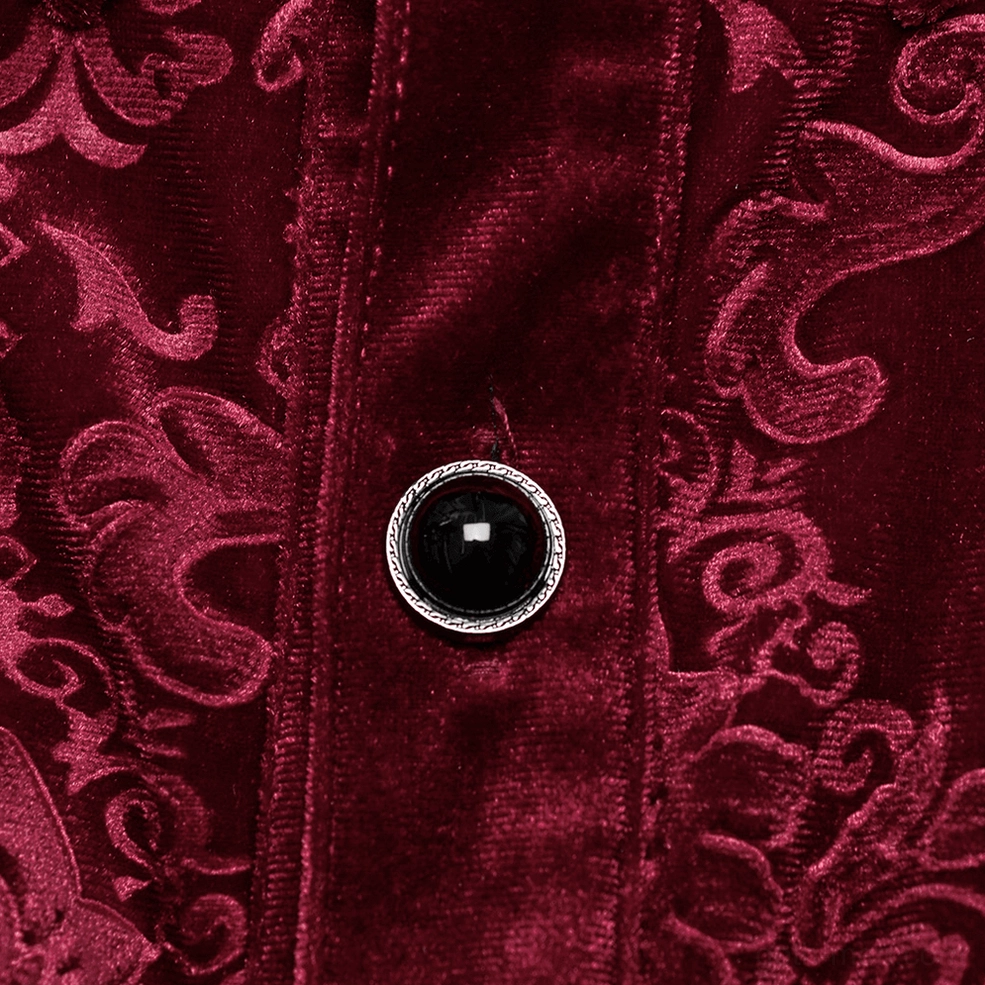 Close-up macro detail of red velvet embossed button and fabric texture showing baroque damask pattern and black silver-rimmed button