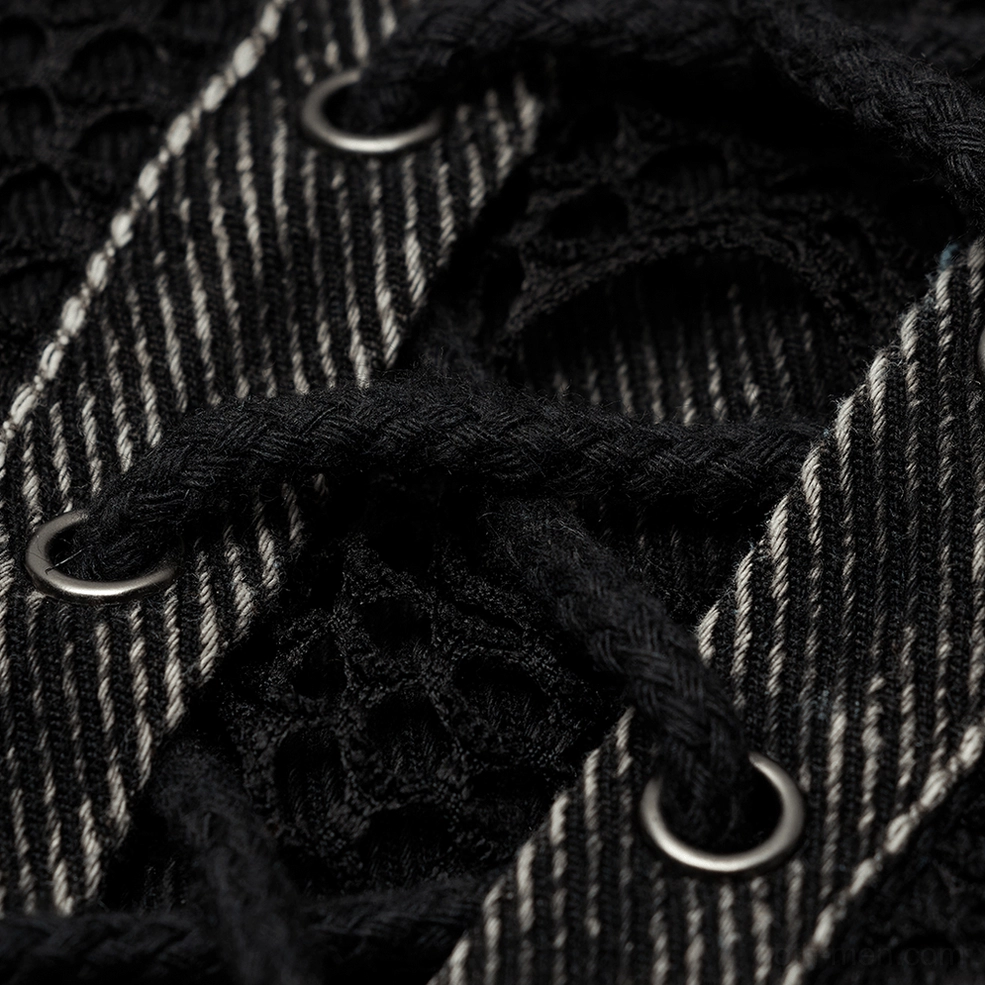 Close-up macro shot of gothic denim vest hardware - metal eyelets, lace-up rope, and striped denim texture