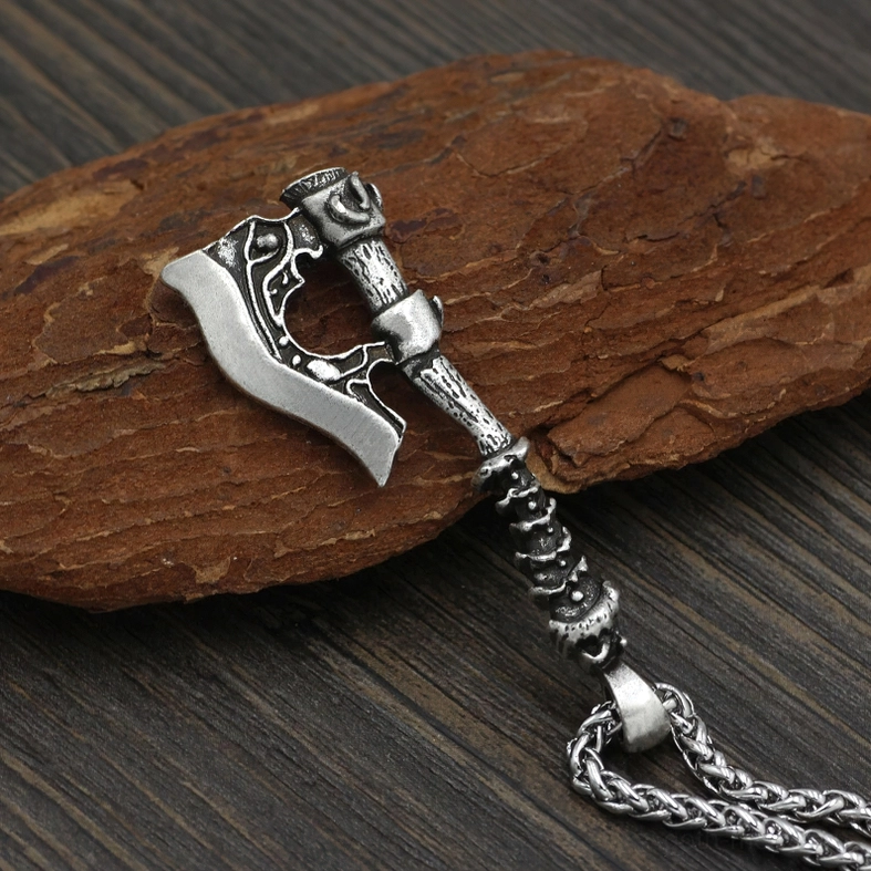 Silver gothic Viking axe pendant necklace with carved details and sliding bead accent on chain, side oblique angle on wood background