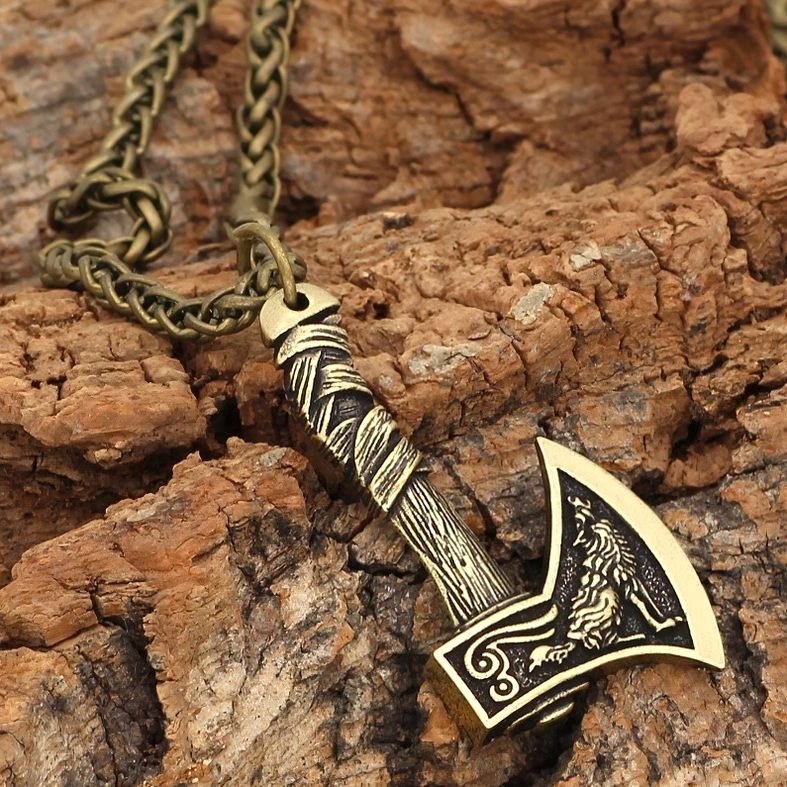 Bronze gothic Viking axe pendant with wolf engraving and wrapped handle, overhead flat lay on natural wood bark background