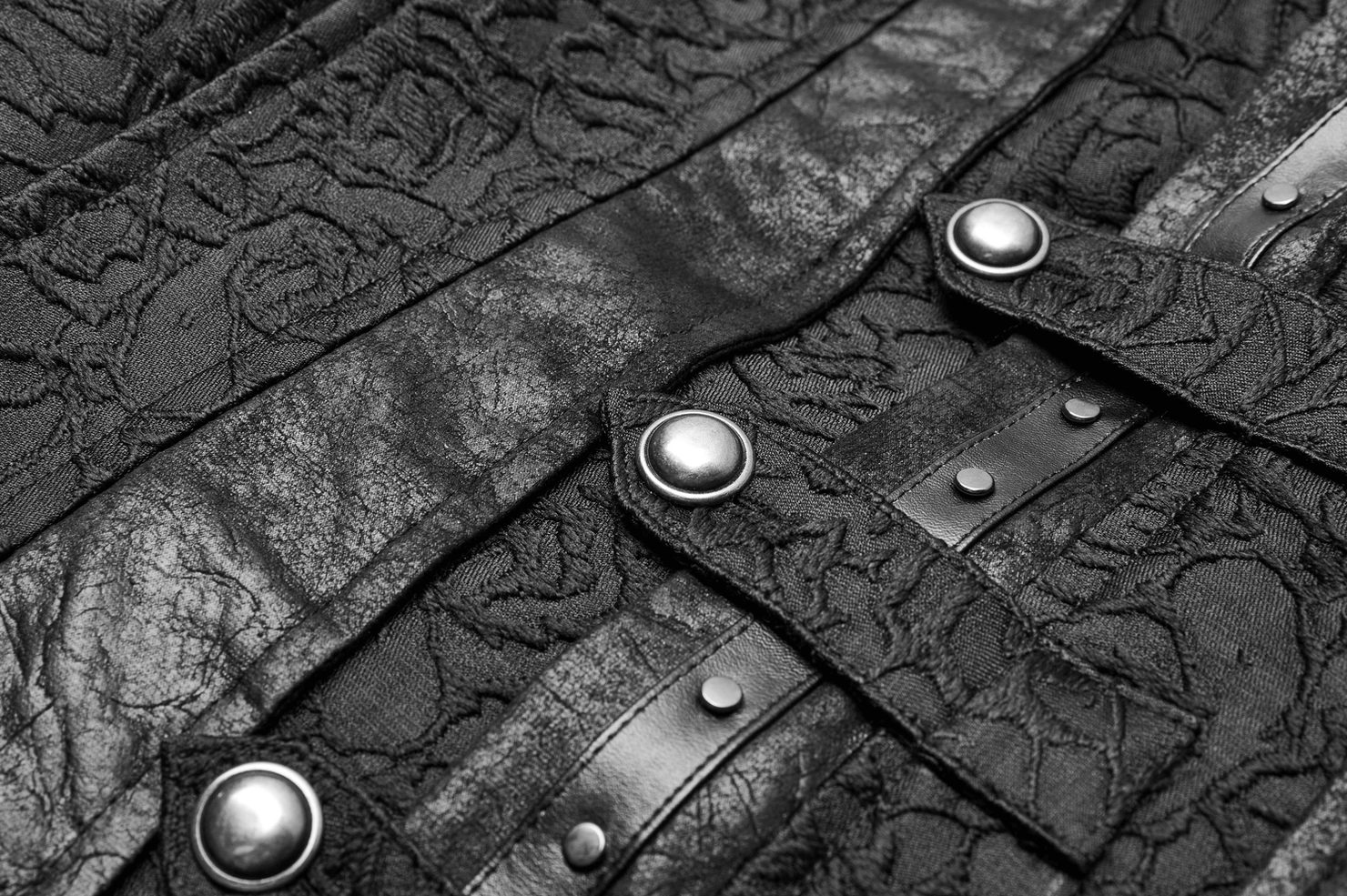 Close-up detail of black gothic waistcoat showing metal snap buttons, faux leather trim accents, and floral jacquard weave
