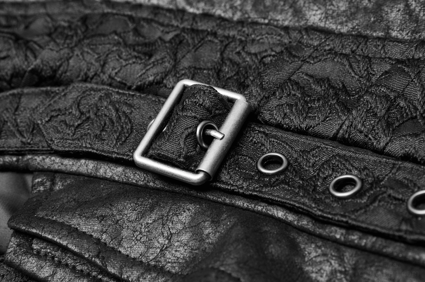 Close-up of black gothic waistcoat metal buckle hardware, eyelet fasteners, and textured fabric construction