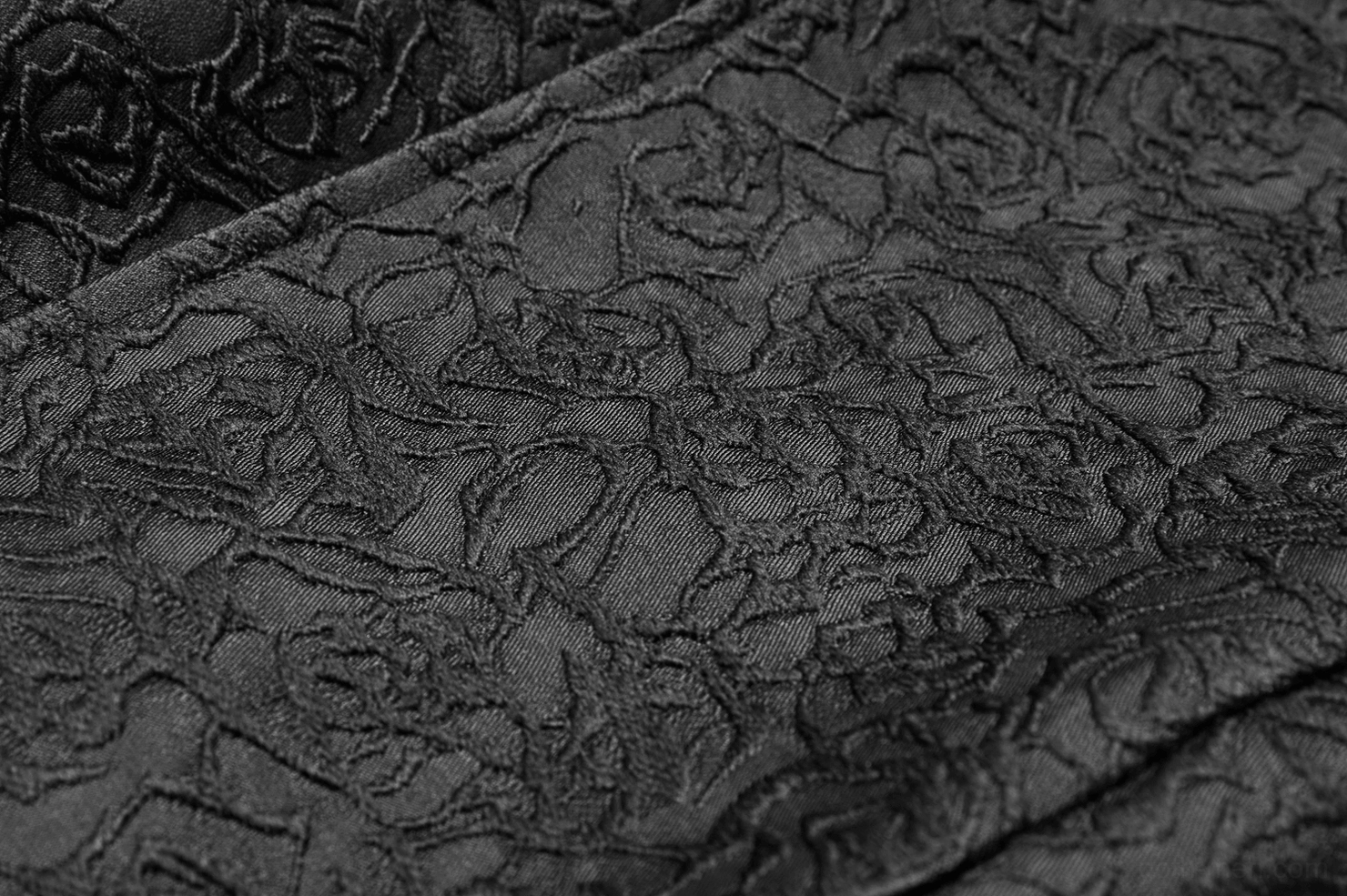 Extreme close-up of black gothic waistcoat showing intricate floral jacquard weave texture and matte finish