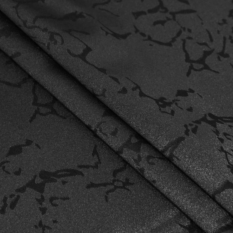 Close-up detail of black jacquard fabric showing embossed gothic floral pattern and woven texture