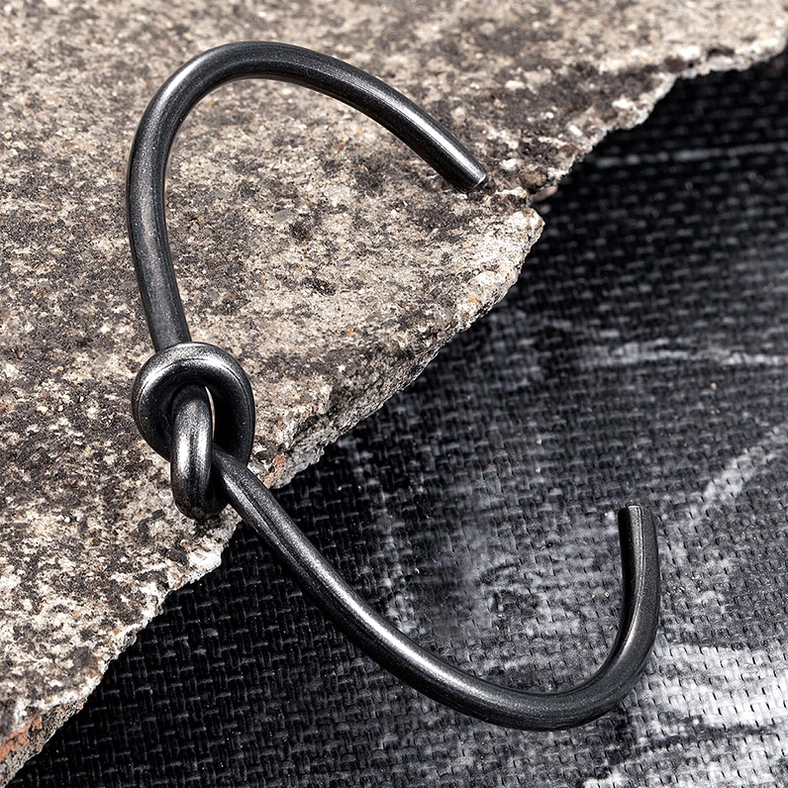 Detailed side view of matte black knotted open cuff bracelet showing oxidized metal finish texture