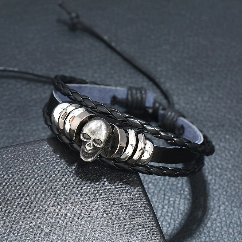 Three-quarter view of black leather skull bracelet showing flat band and braided strands with adjustable pull cord fastening system