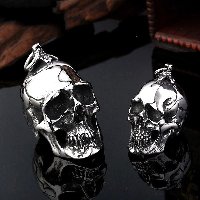 Close-up front view of two skull pendants showing precise dental and bone work in polished silver