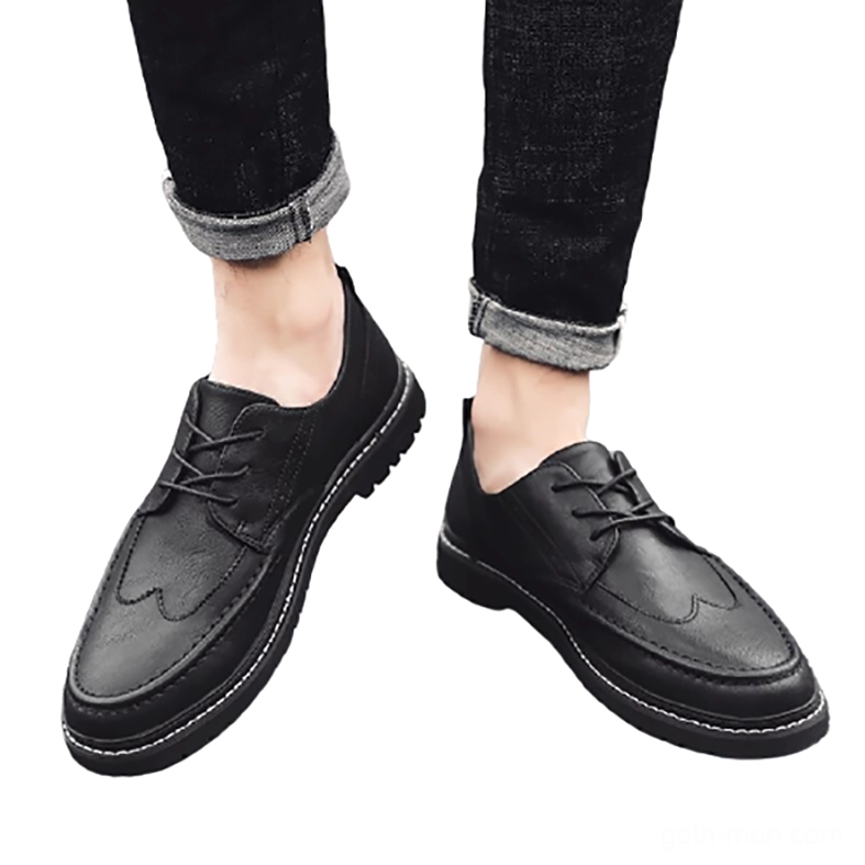 Styled flat lay of black gothic men's leather shoes worn with rolled black jeans, overhead view showing non-slip sole