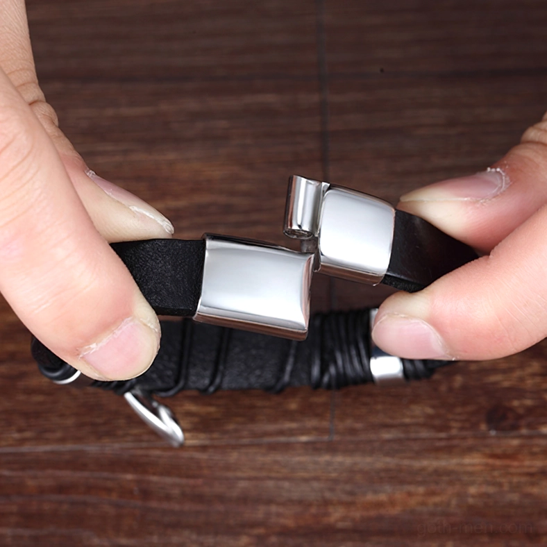 Opened magnetic clasp gothic leather bracelet held by two hands showing braided leather and stainless steel construction on wooden table