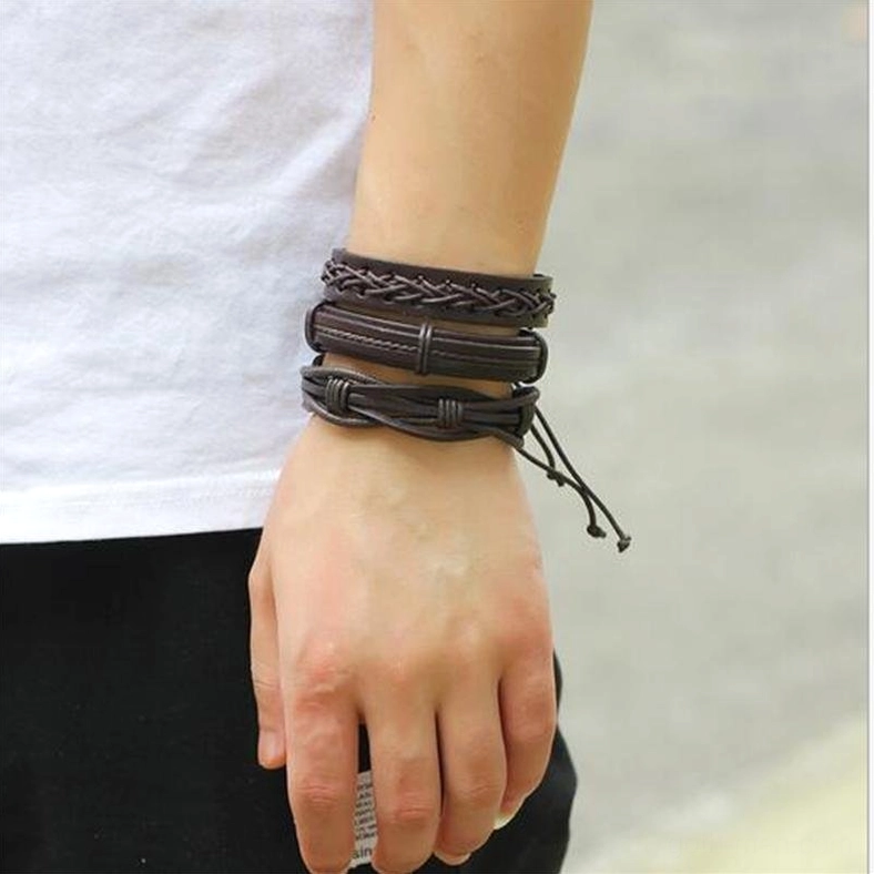 Close-up of men's wrist wearing stacked brown leather gothic braided bracelets with rope details street fashion