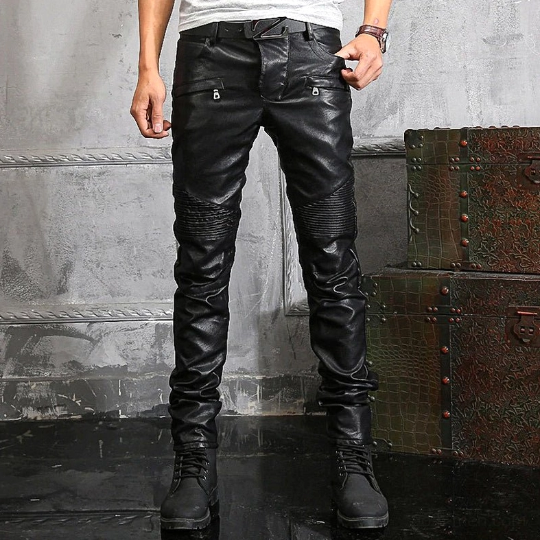 Male model wearing black ripped faux leather moto pants full body front view in industrial setting