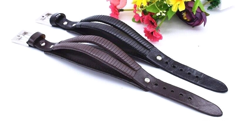 Men's leather cuff bracelet straps overhead view with decorative floral props, adjustable buckle holes, gothic aesthetic